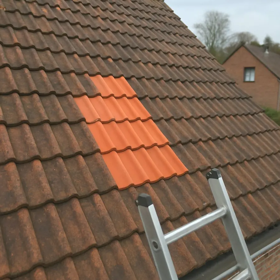 Enkele nieuwe pannen tussen oude pannen op een hellend dak